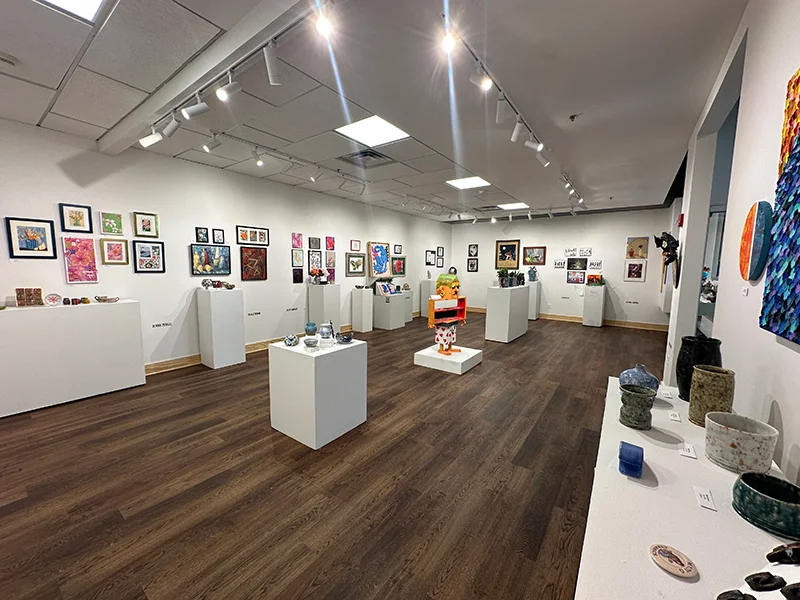 The Suraci Art Gallary with a sculpture in the middle and paintings on the wall on both sides