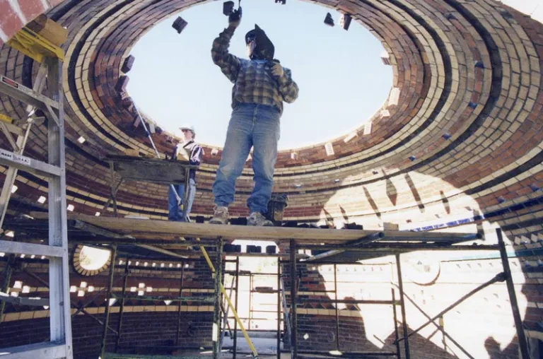 Two people work on constructing a stone dome.