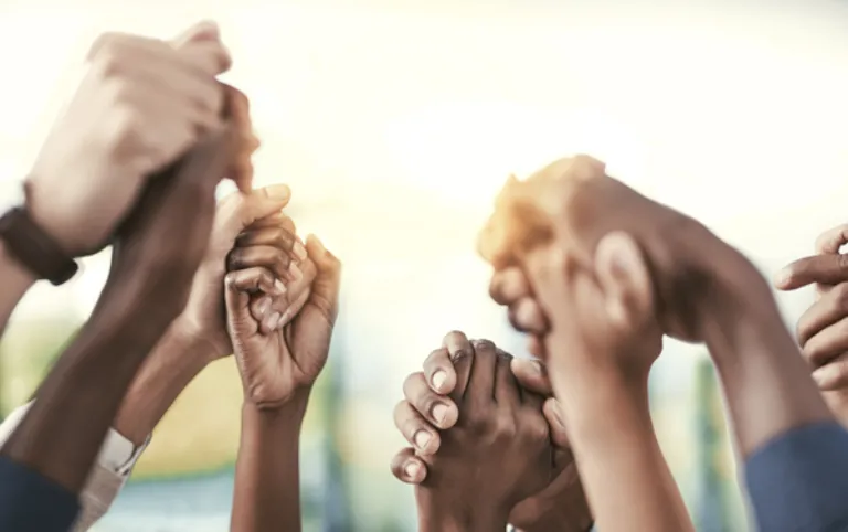 Different ethnicities holding hands in the air.