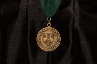 Gold Medal with Marywood seal hanging from a green ribbon against black academic attire Marywood University to Award 39 Endowed Medals of Recognition to Graduates