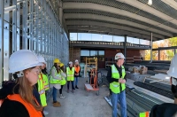 Students in hard hats and reflective vests are pictured at the construction site of a campus facility, the Pascucci Health Sciences Pavilion. Construction Management Program Celebrates 1st Anniversary with Special Announcement