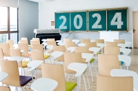 The back view of an empty classroom with 2024 written on the chalkboard.