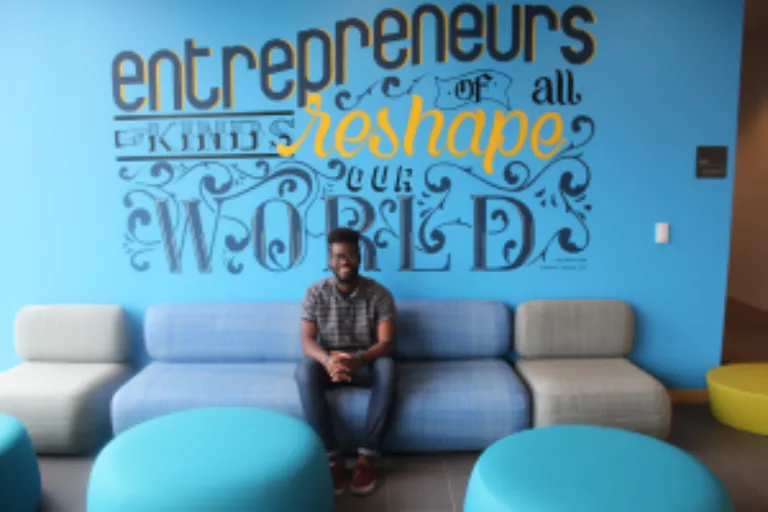 Emmanuel Adjei Poses in front of the Mural he co-created.