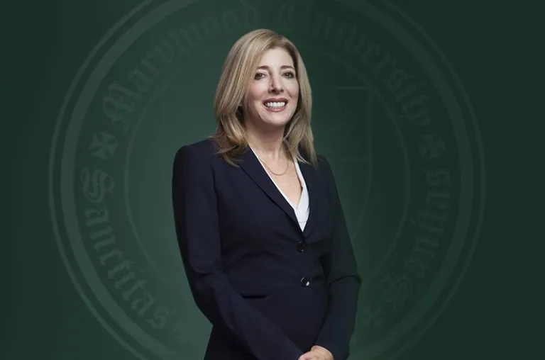 Marywood's 13th President Lisa A. Lori is pictured in a dark blue suit against a green backdrop with the Marywood seal.