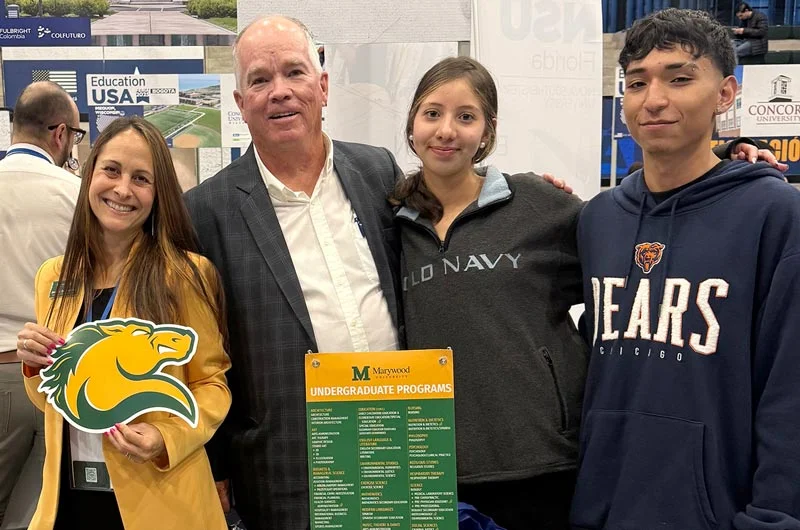 A woman and man with two adolescent students are pictured holding Marywood University branded materials, including a horse (Pacer) die-cut information card. Marywood Explores Global Initiatives in Colombia