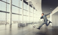 Businessman kicking a a soccer ball in an office setting. Sports Industry Careers That Keep the Game Going