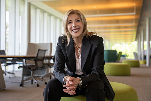 President  Lori sitting down, smiling, and wearing a black suit